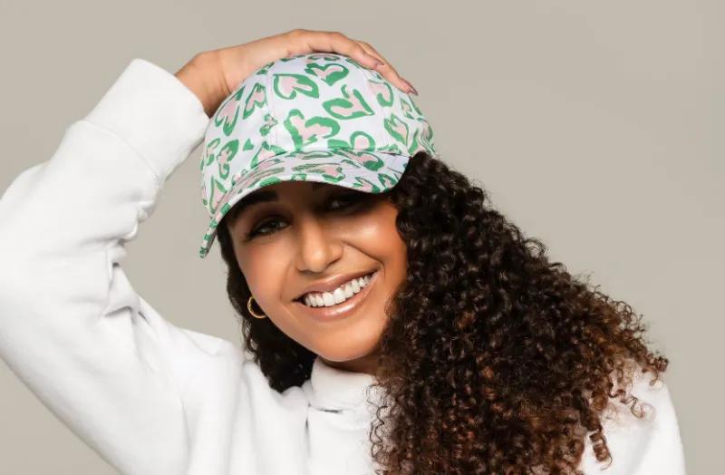 Embellished Pretty Girls Cap with pink and green hearts on white background and curved brim