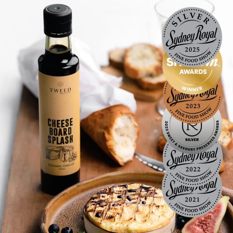 Tweed Real Food Cheeseboard Splash Balsamic Vinegar, a bottle of rich blueberry balsamic beside a cheese platter