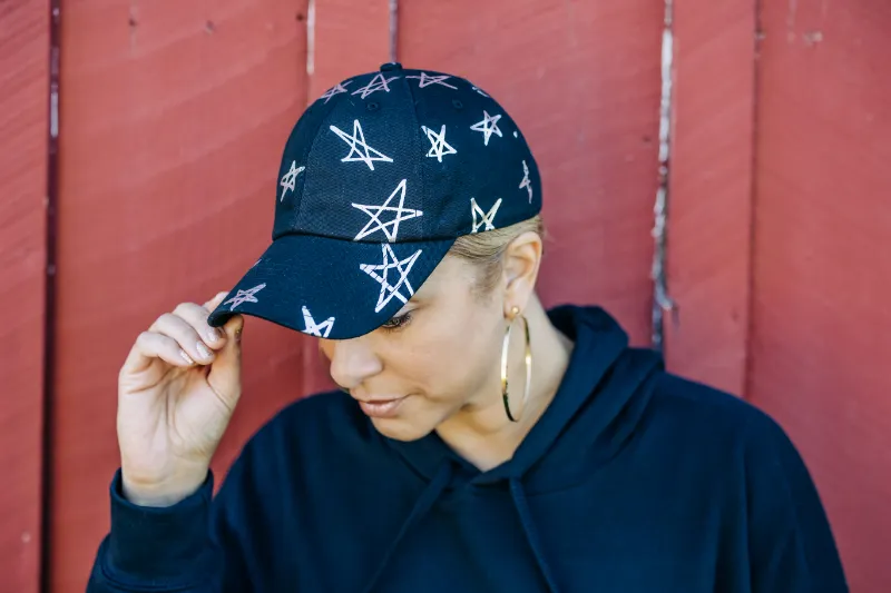 Embellished Baby I'm A Star Cap in black cotton with metallic silver star pattern and curved brim
