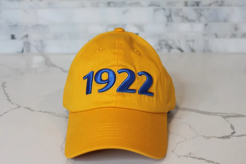 Embellished 1922 Cap in yellow gold cotton with blue and gold embroidered detail and curved brim