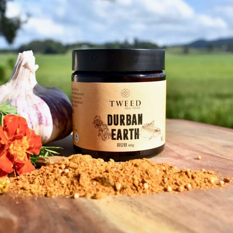 Tweed Real Food Durban Earth Curry Rub tin beside spiced cooked meat